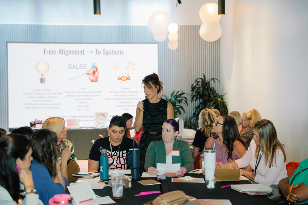 Business operations workshop discussing systems, sales, and team alignment during a group training session.