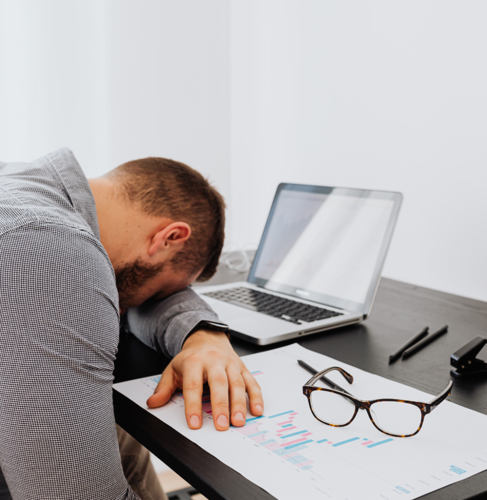 Exhausted founder resting at desk with laptop and reports, showing founder decision fatigue.