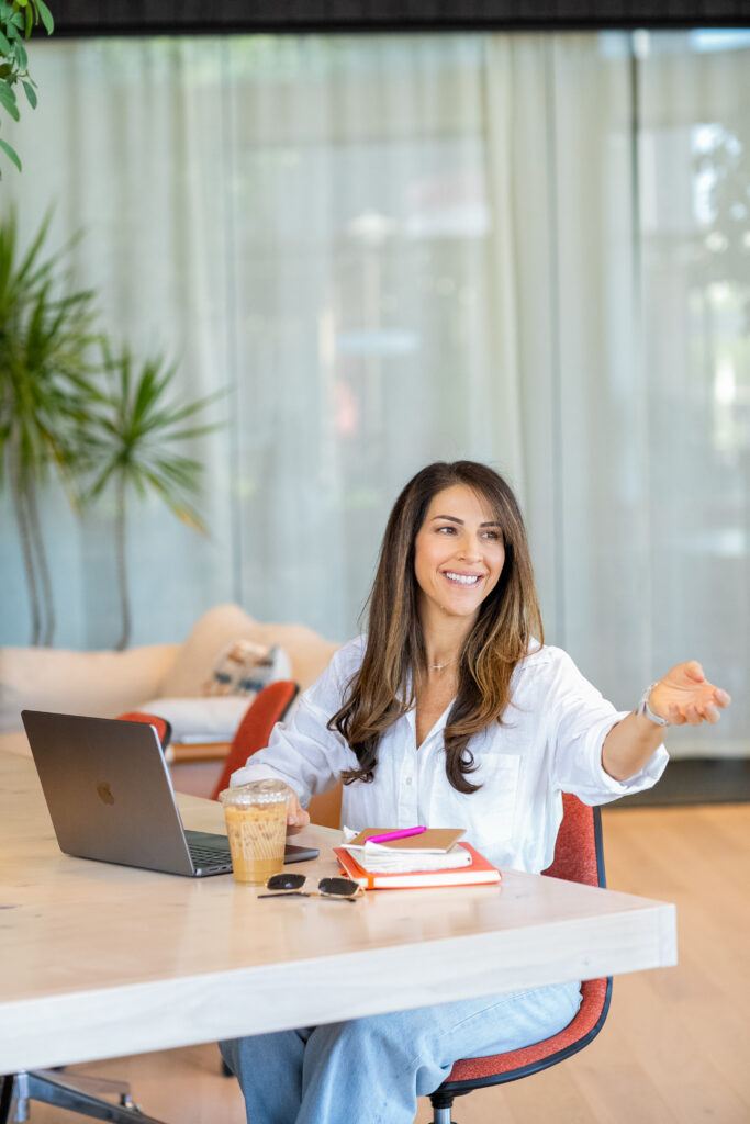 A founder working at a laptop and welcoming a conversation, representing hiring for business growth and team expansion.