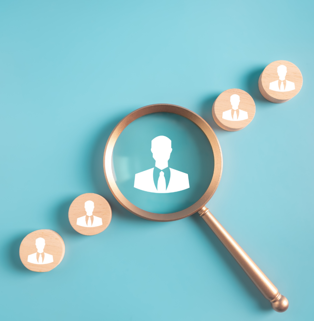 Magnifying glass focusing on a candidate icon among several profiles, representing the process of hiring more people for business growth.