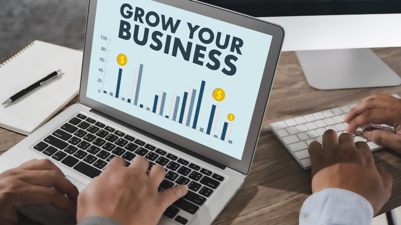 Hands using a laptop displaying business growth charts, illustrating the process of scaling a business.