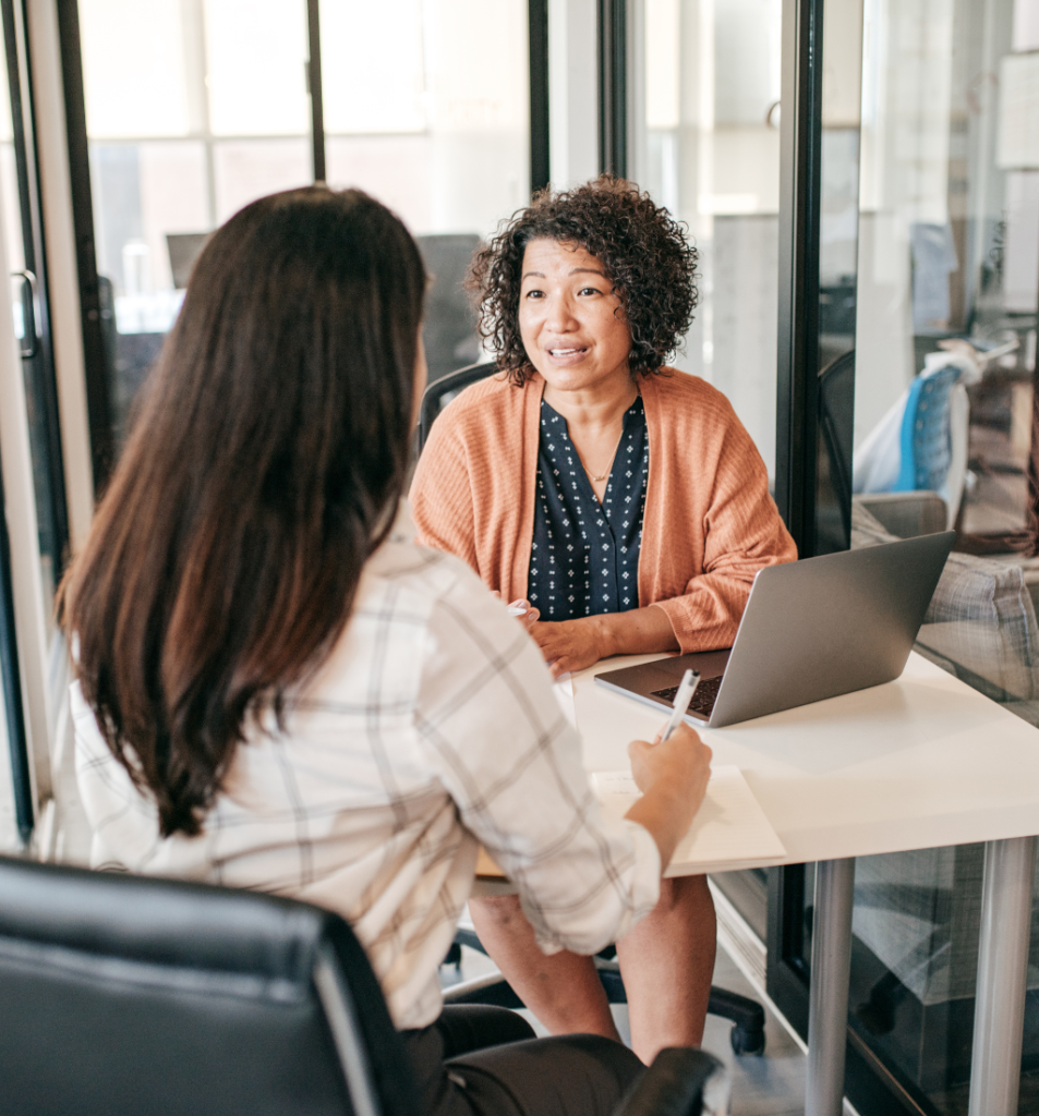 Two professionals discussing business processes in an office, highlighting the importance of systems before hiring.