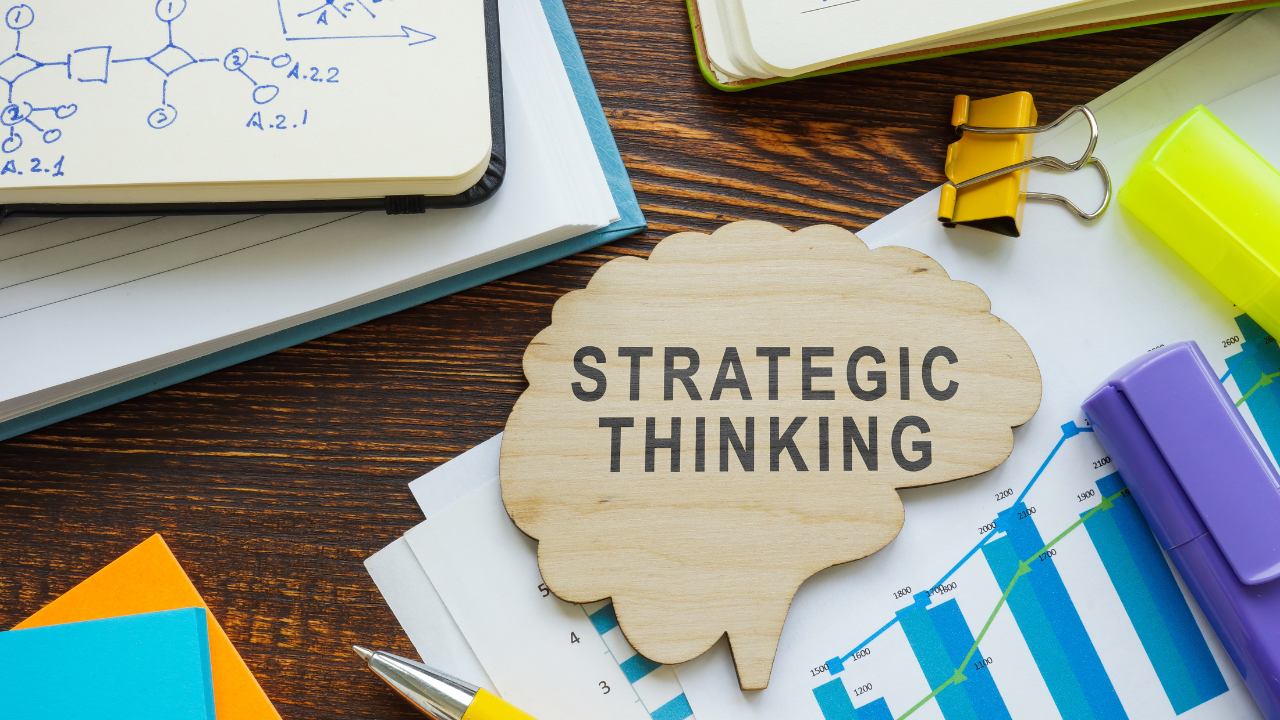 Founder strategic thinking concept featuring a wooden brain-shaped sign on a desk surrounded by business charts, notebooks, and office supplies.