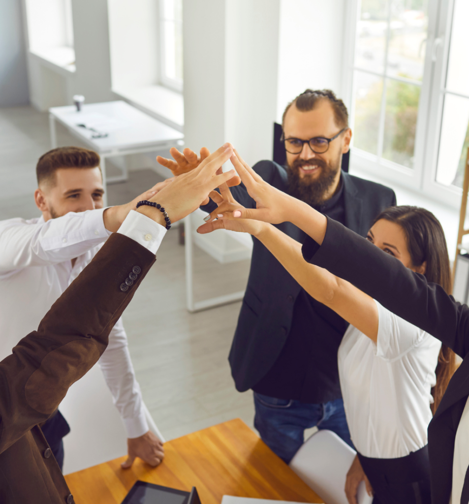 Leadership effectiveness illustrated by a team of professionals joining hands in an office, symbolizing teamwork, collaboration, and shared business goals.
