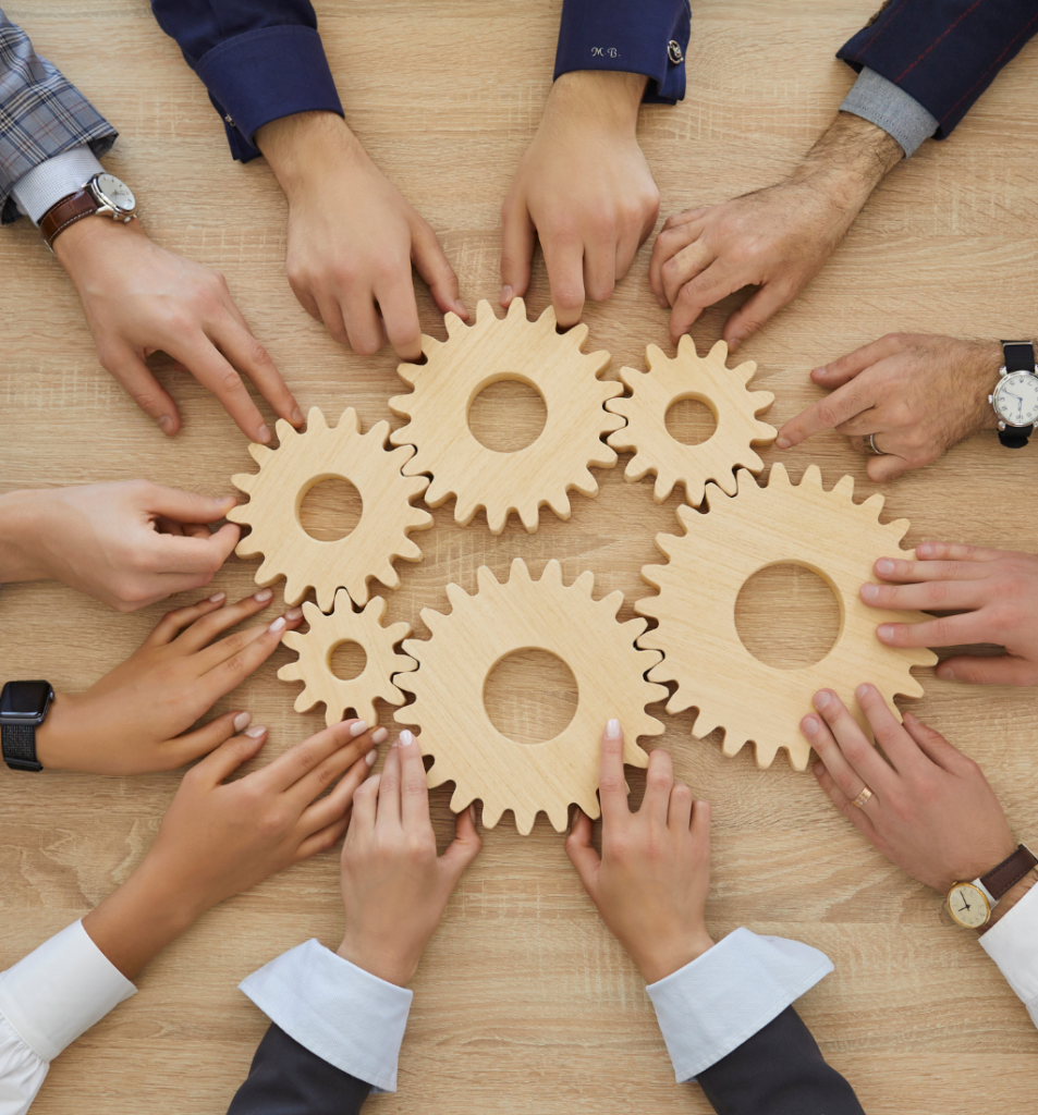Team members arranging interlocking wooden gears to represent collaboration and effective operational process design.
